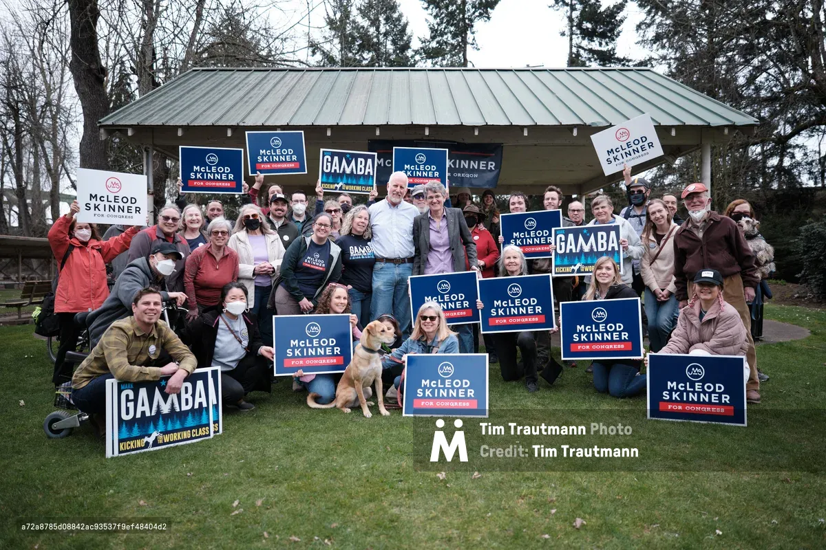 A large group of political supporters gathered outdoors in Oregon City, Oregon, holding campaign signs for McLeod Skinner and Gamba candidates. The diverse group of approximately 30-40 people poses in front of a covered pavilion structure, with many wearing casual outdoor clothing and some face masks, creating an energetic grassroots campaign atmosphere.