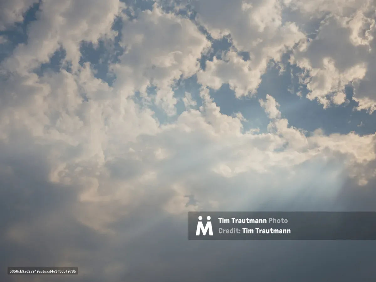 A moody sky filled with thick, billowing gray and white clouds with patches of blue sky visible through the cloud cover, captured in Portland, Oregon. The atmospheric conditions create a dramatic overcast scene with varying cloud densities and natural lighting.