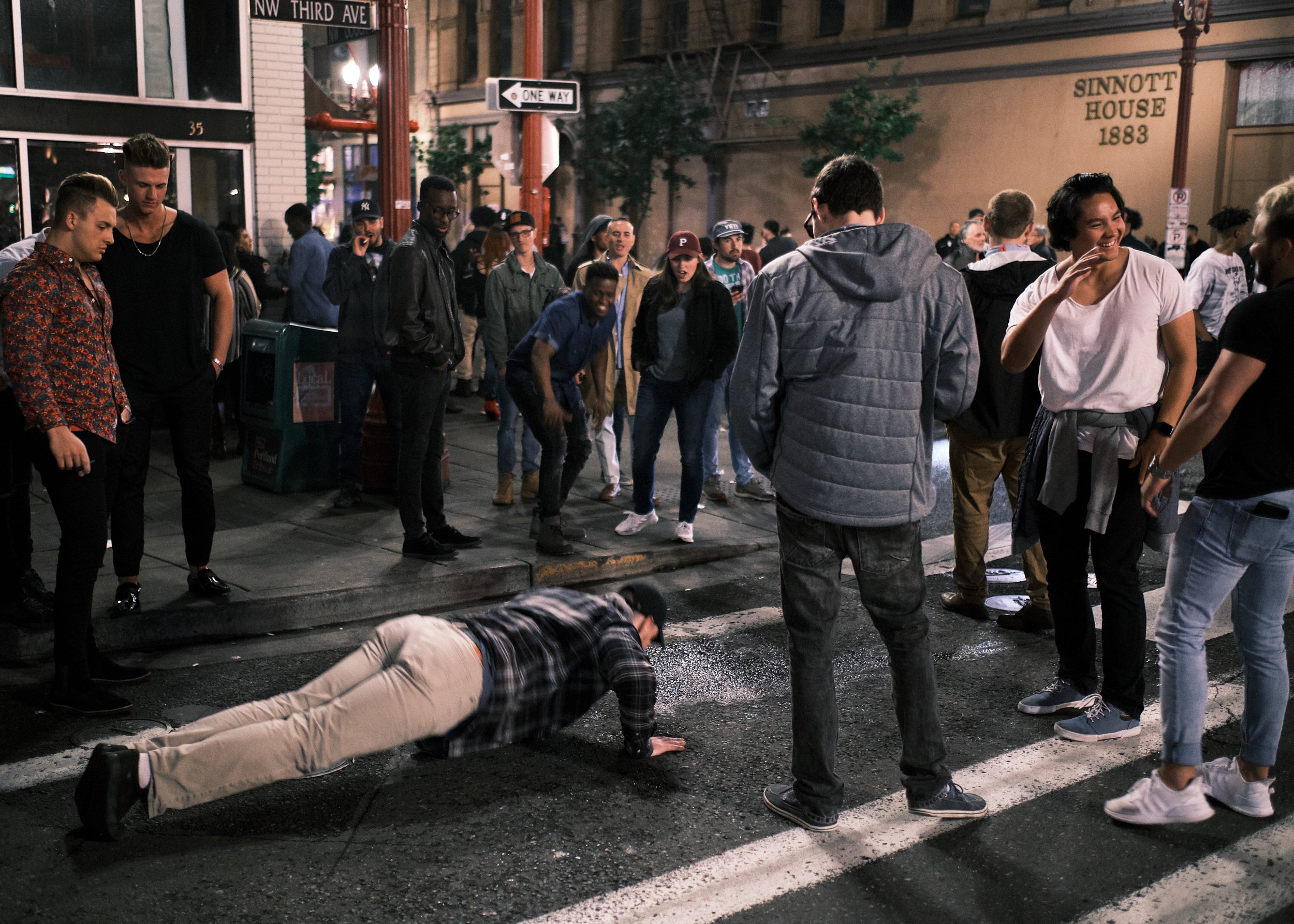 A crowd is gathered on the street late at night after entertainment venues have closed for the night.