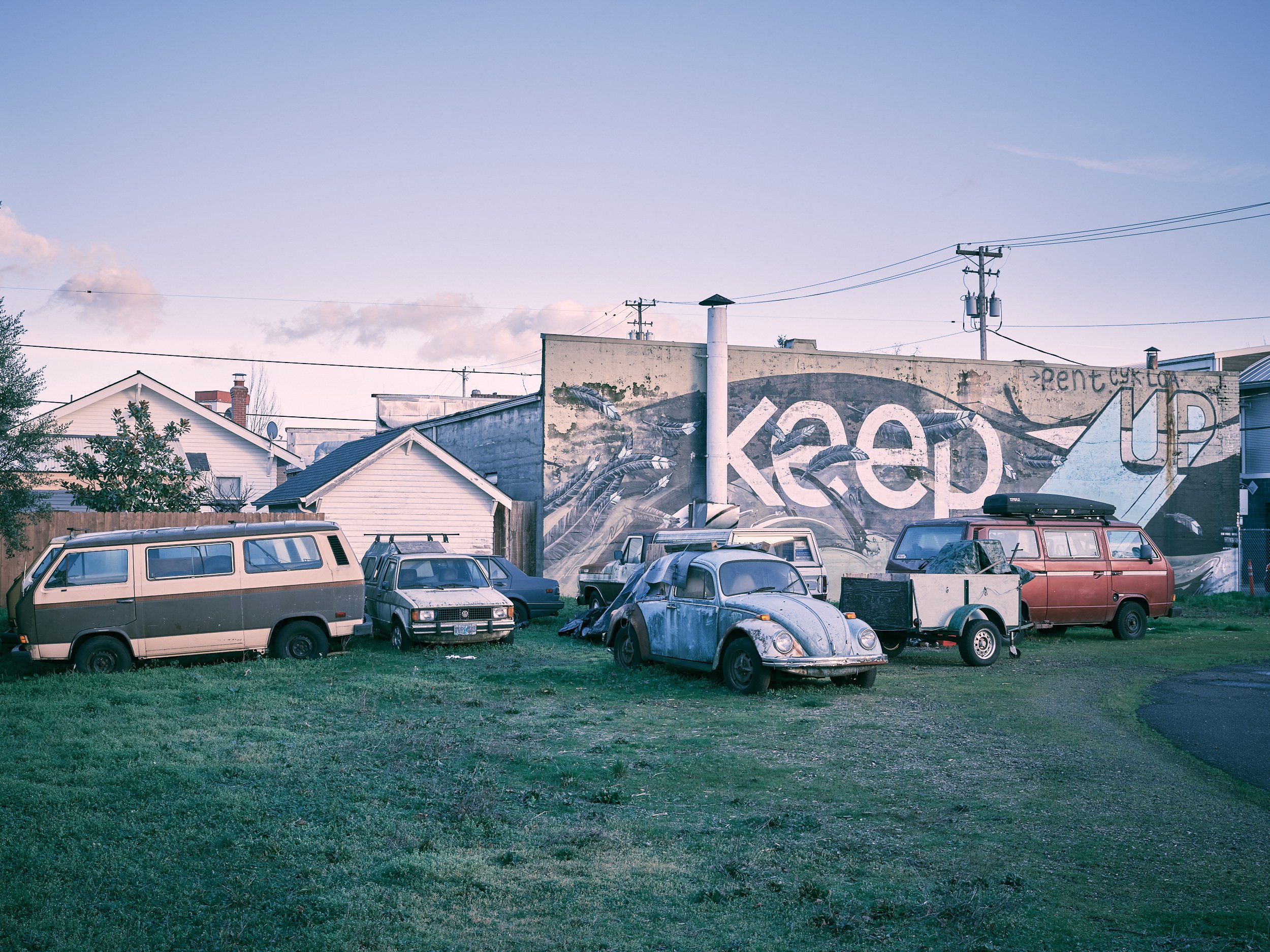 A weathered mural - Keep your chin up - in the Alberta Arts District in Portland, Oregon. Old cars are parked in front of the mural.