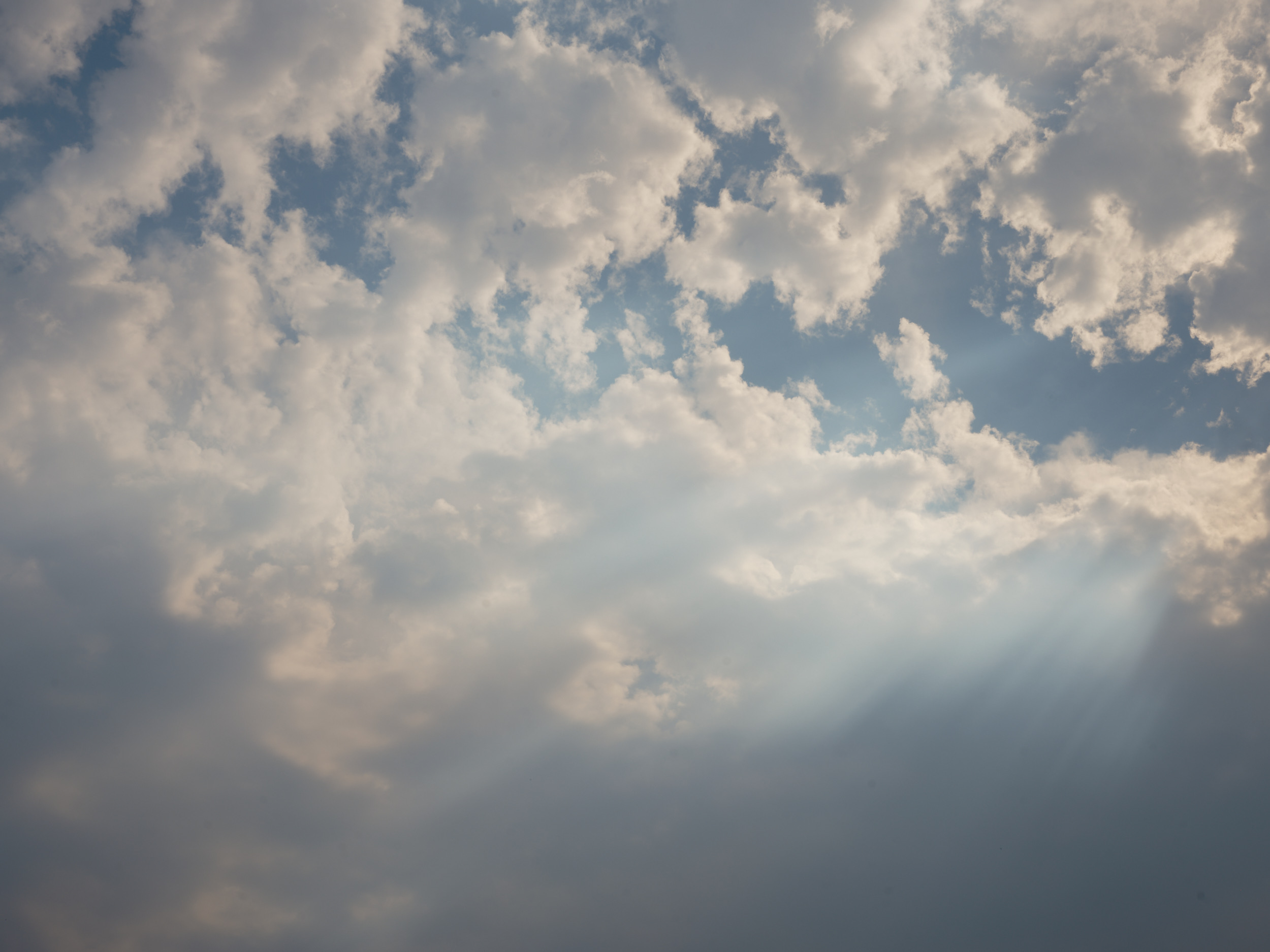 A moody sky filled with thick, billowing gray and white clouds with patches of blue sky visible through the cloud cover, captured in Portland, Oregon. The atmospheric conditions create a dramatic overcast scene with varying cloud densities and natural lighting.