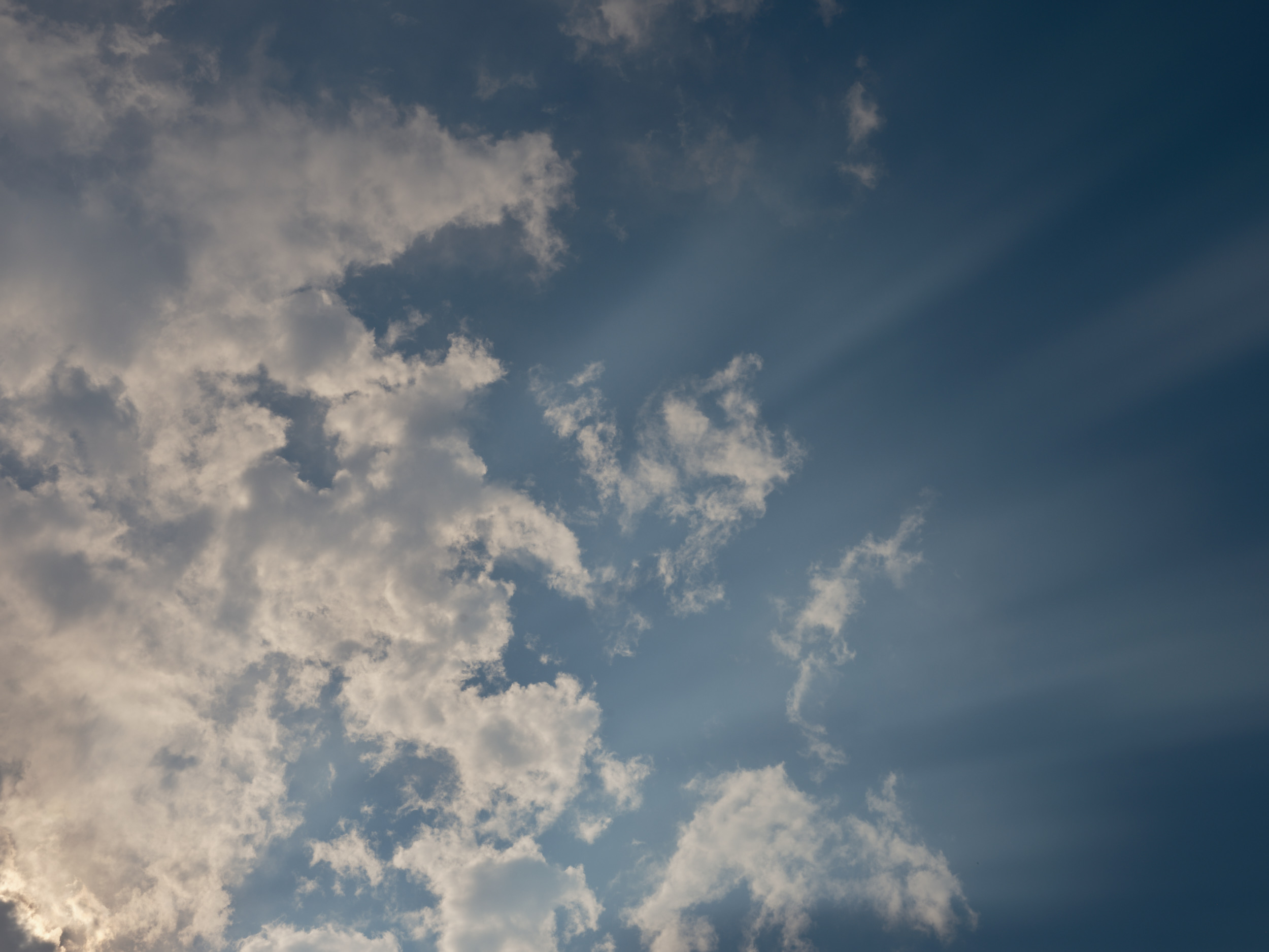 A dramatic sky filled with billowing white and gray clouds against a deep blue backdrop, captured over Portland, Oregon. The clouds show various textures and densities, creating a dynamic atmospheric scene with natural lighting variations.